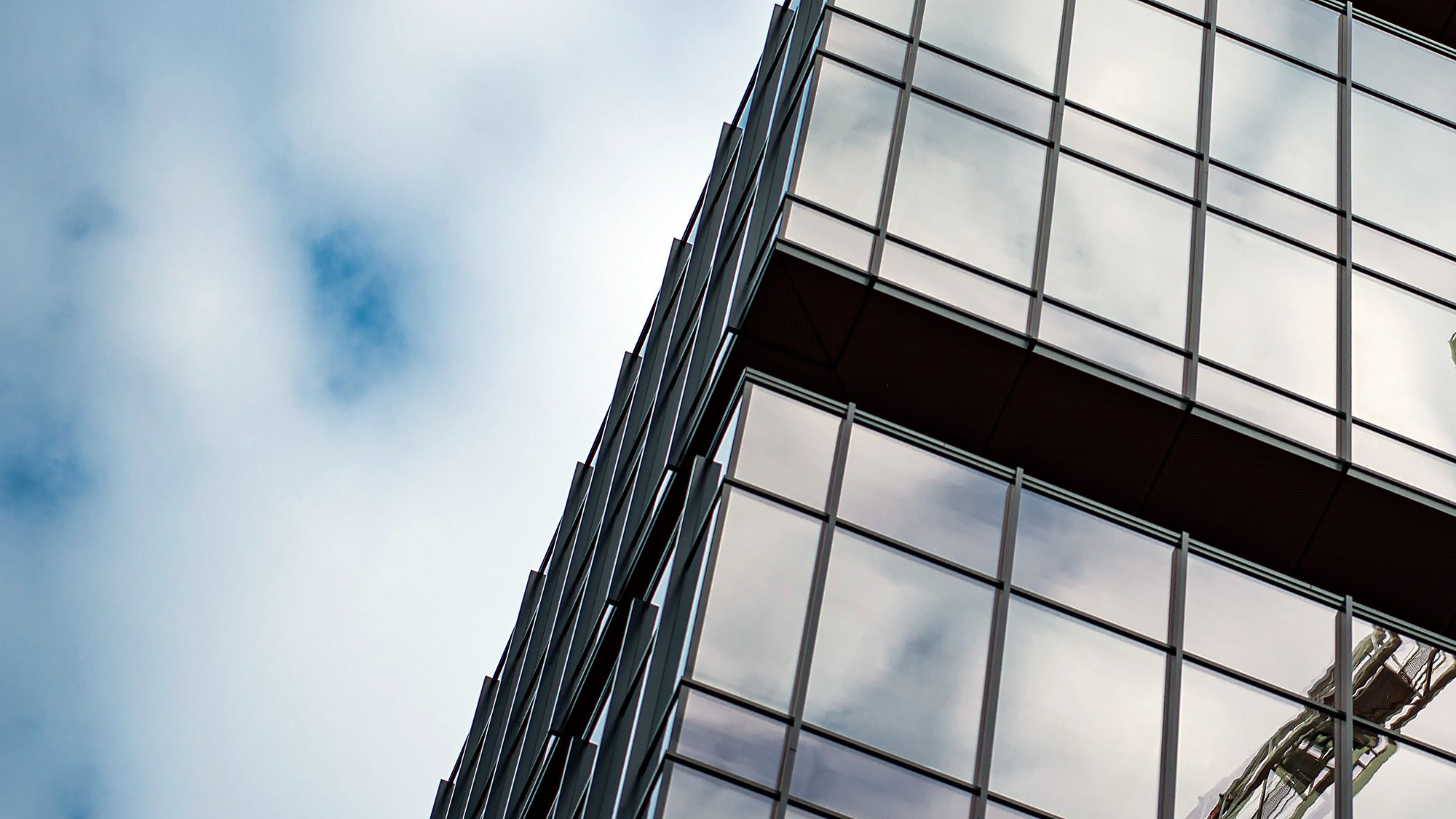 A glass facade reflecting clouds