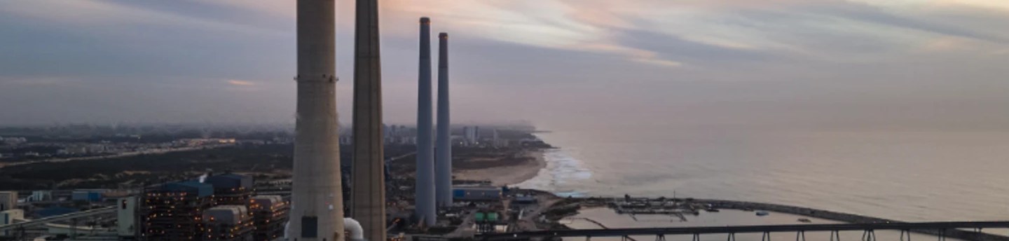 Aerial view of an industrial coastline with tall stacks at dusk